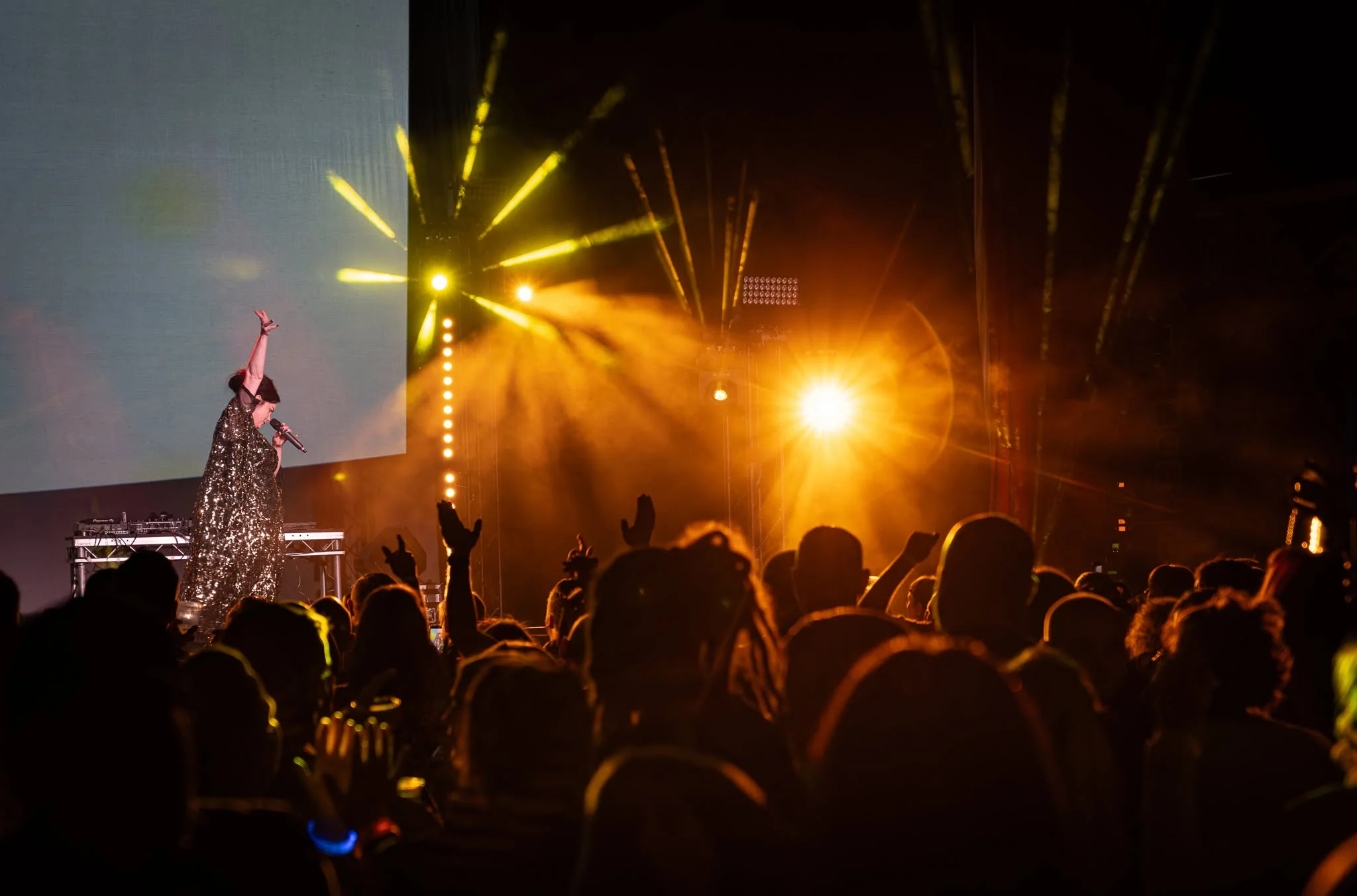 Live performer and audience under amber stage lighting